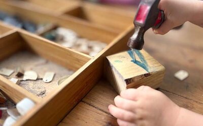 Ein Kind hämmert einen Nagel in einen Holzklotz; Bild: Renee Mitchell auf Unsplash