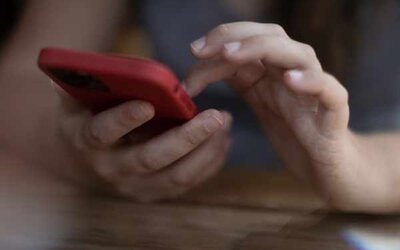 Hände halten ein rotes Smartphone.