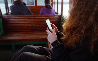 Eine Frau sitzt auf einer Bank und schaut auf ein Handy