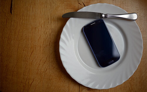 Smartphone auf einem leeren Teller mit Messer