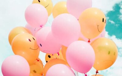 Foto von rosanen und orangenen Luftballons, die mit lachenden und traurigen Smileys bedruckt sind; Bild: Madison Oren auf Unsplash
