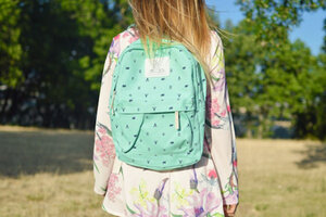 Frau im bunt-geblümten langärmeligen Minikleid mit grünem Rucksack; Bild: Tamara Bellis Frau im bunt-geblümten langärmeligen Minikleid mit grünem Rucksack; Bild: Tamara Bellis