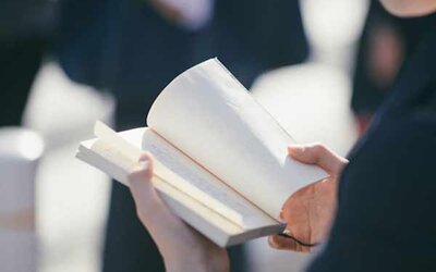 Frau mit offenem Buch in den Händen.