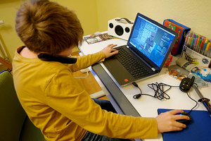 Junge spielt am Notebook und telefoniert gleichzeitig; Bild: Find-das-Bild.de / Michael Schnell