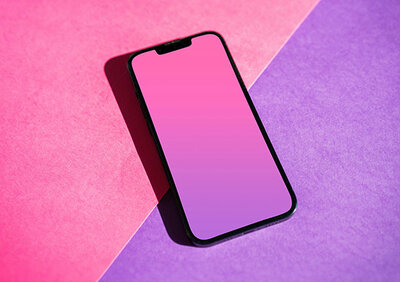 Ein schwarzes Smartphone liegt auf einem lila-rosa Hintergrund.