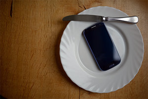 Smartphone auf einem leeren Teller mit Messer