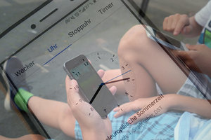 Uhr und am Handy spielende Kinder; Bild: Find-das-Bild.de/Internet-ABC