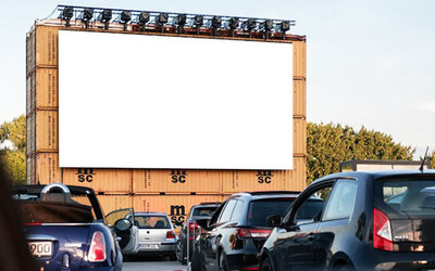 Autos stehen vor einer großen Leinwand.