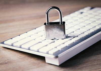 Silbernes Vorhängeschloss auf weißer Tastatur.